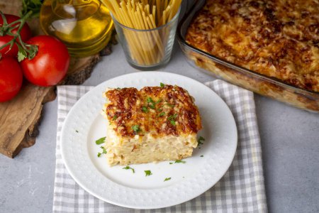 Photo for Pasta casserole bechamel sauce topped with melted mozzarella cheese and served in a white baking dish on a table (Turkish name; firinda makarna or firin makarna) - Royalty Free Image