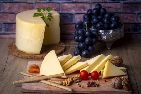 Photo for Kashar cheese or kashkaval cheese on wood floor. Cheese slices on the serving board - Royalty Free Image