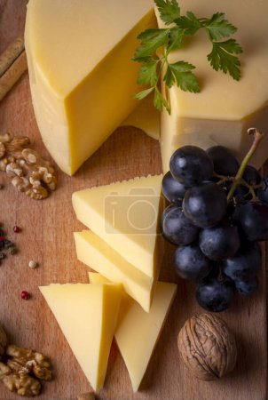 Foto de Queso kashar o queso kashkaval en el suelo de madera. Rebanadas de queso en la tabla de servir - Imagen libre de derechos