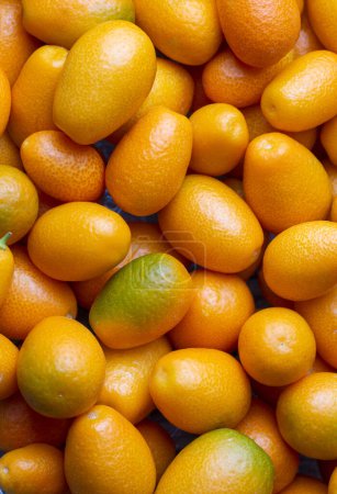 Téléchargez les photos : Vue de dessus du bouquet de kumquats frais sur le marché des aliments biologiques. Certains kumquats sont coupés. - en image libre de droit