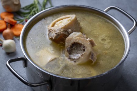 Foto de Boiled bone and broth. Homemade beef bone broth is cooked in a pot on. Bones contain collagen, which provides the body with amino acids, which are the building blocks of proteins. - Imagen libre de derechos