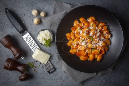 Foto de Gnocchi de patata de comida italiana tradicional con salsa de tomate, queso parmesano y albahaca fresca en la mesa oscura. Vista superior. Alimento saludable. - Imagen libre de derechos