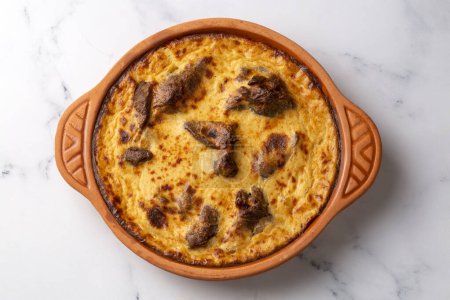 Photo for Tave kosi is a national Albanian dish of baked lamb and rice with yoghurt close-up in a pan on the table. horizontal top view from above. Turkish name; Elbasan tava - Royalty Free Image
