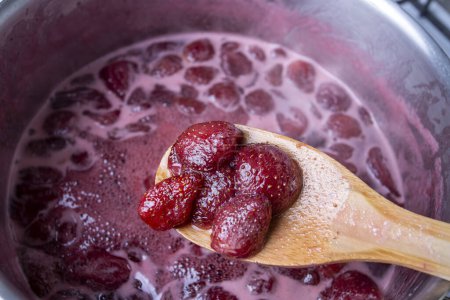 Photo for Cooking strawberry jam in a silver pot on the stove - Royalty Free Image