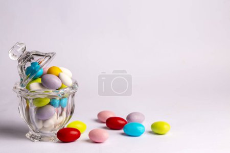 Photo for Colorful almond candies in the stylish,crystal candy bowl on white with copy space.The Sugar Feast concept. (Turkish name; Ramadan - Ramazan bayrami, Seker bayrami) - Royalty Free Image