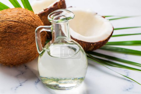 Photo for Bottle of coconut oil and fresh coconuts with palm leaf - Royalty Free Image