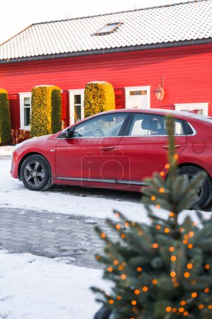 Photo for Tnsberg, Norway - December 2, 2023: orange red Hyundai Ioniq electric car charging next to the norwegian house - Royalty Free Image