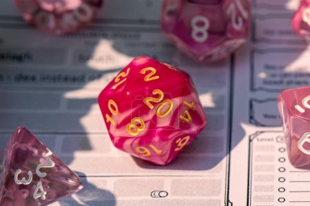 Photo for Close-up image of a pink role-playing gaming die on a character sheet - Royalty Free Image