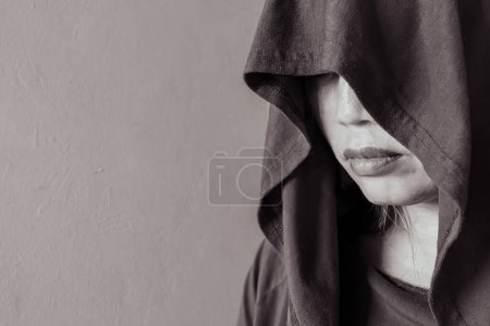 A profile view of a woman shrouded in a hood, her gaze hidden, captured in stark black and white