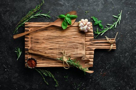 Photo for Banner of homemade cooking recipes. Kitchen old wooden board, spices and herbs, free space for text. On a black stone background. Top view. - Royalty Free Image