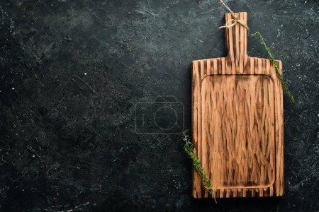 Photo for Kitchen old wooden board, free space for text. On a black stone background. Top view. - Royalty Free Image