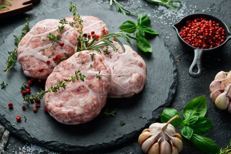 Photo for Caul-Fat Meatballs raw burger cutlet handmade. On a stone board. On a black background. Top view. - Royalty Free Image