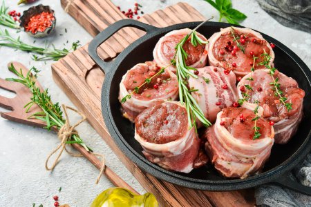 Photo for Raw meat medallions wrapped in bacon. in a pan, ready to cook. On a concrete background. Side view. - Royalty Free Image
