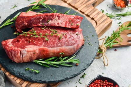 Téléchargez les photos : Vieilli steak à la striploïne juteuse. De la viande. Sur un fond de pierre noire. Vue latérale. - en image libre de droit
