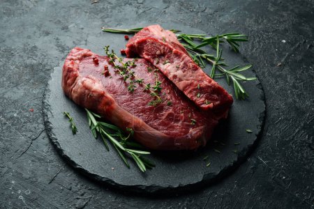 Téléchargez les photos : Vieilli steak à la striploïne juteuse. De la viande. Sur un fond de pierre noire. Vue latérale. - en image libre de droit