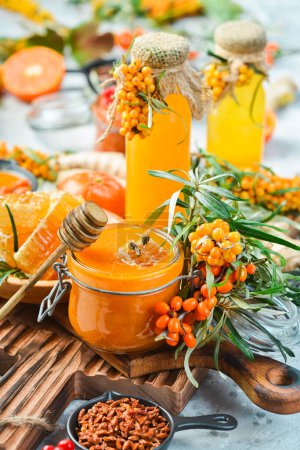 Photo for Freshly collected autumn honey in a jar. Sprigs of sea buckthorn and autumn berries. On a dark background. Side view. - Royalty Free Image