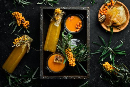 Photo for A bottle of homemade drink with honey, sea buckthorn and vitamin C. Autumn drinks. On a dark background. Top view. - Royalty Free Image