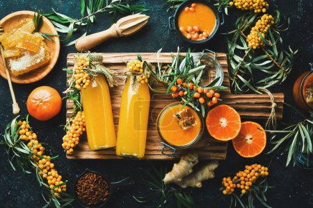 Photo for A bottle of homemade drink with honey, sea buckthorn and vitamin C. Autumn drinks. On a dark background. Top view. - Royalty Free Image