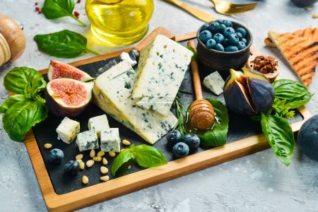 Photo for Traditional blue cheese, figs, blueberries and honey in a plate. On a concrete background. Side view. - Royalty Free Image