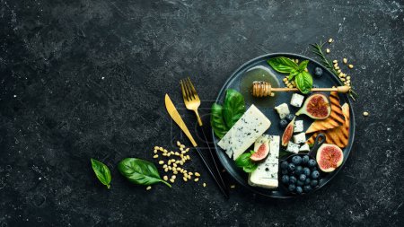 Foto de Queso azul, higos, arándanos y miel en un plato. Sobre un fondo concreto. Vista superior. - Imagen libre de derechos