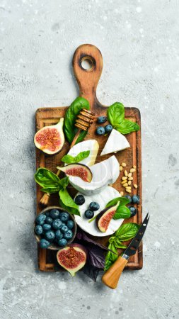 Photo for Brie cheese with honey and figs on a wooden board. On a concrete background. Top view. - Royalty Free Image