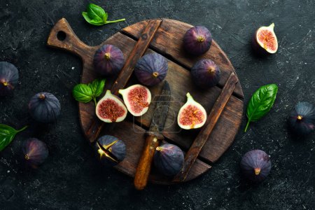 Photo for Fresh ripe figs with green leaf and on dark table black background. Space for text. Top view. - Royalty Free Image
