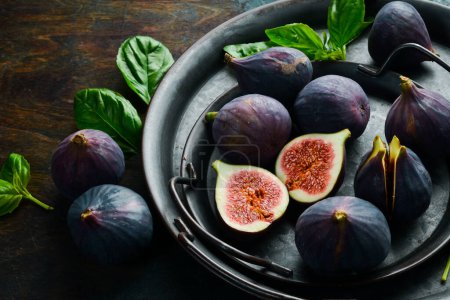 Téléchargez les photos : Un bol de figues fraîches. Fruits tropicaux frais. Sur un fond sombre. Espace pour le texte. - en image libre de droit