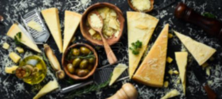 Photo for Defocused food background. Set of hard cheeses with cheese knives on black stone background. Parmesan. Top view. Free space for your text. - Royalty Free Image