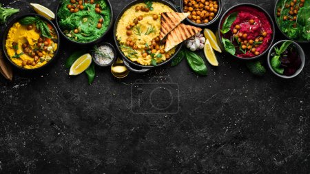 Photo for Colorful hummus bowls background. Different kinds of dips. Traditional hummus, herb hummus, beetroot hummus. On a concrete black background. - Royalty Free Image