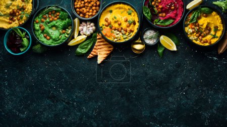 Photo for Colorful hummus bowls background. Different kinds of dips. Traditional hummus, herb hummus, beetroot hummus. On a concrete black background. - Royalty Free Image