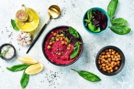 Foto de Hummus rojo de remolacha y garbanzos en un tazón. Recetas veganas basadas en alimentos vegetales. Sobre un fondo concreto. - Imagen libre de derechos