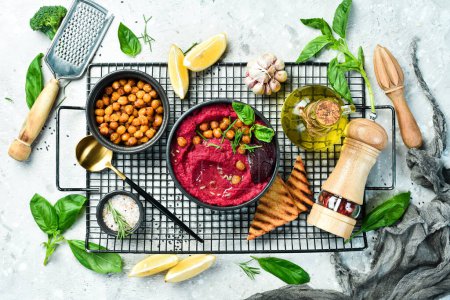 Red hummus from beets and chickpeas in a bowl. Vegan recipes based on plant foods. On a concrete background.