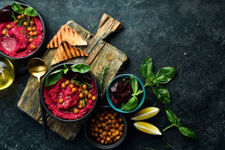 Photo for Beetroot chickpea hummus in a bowl. Red hummus. Healthy vegetarian food. On a concrete black background. - Royalty Free Image