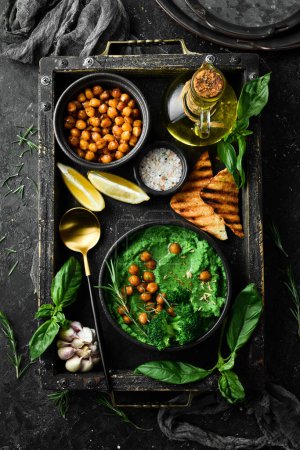 Photo for Basil pesto hummus on a dark wood background. Healthy vegetarian food. On a stone black background. - Royalty Free Image