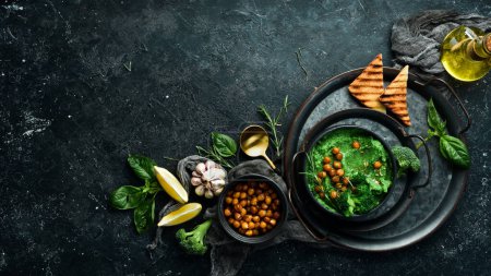 Foto de Hummus de pesto de albahaca sobre un fondo de madera oscura. Comida vegetariana saludable. Sobre un fondo negro de piedra. - Imagen libre de derechos