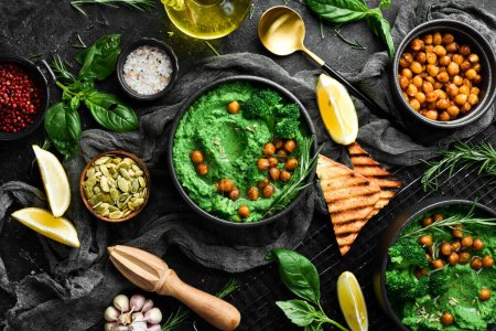 Photo for Green hummus. Hummus from chickpeas and spinach and broccoli, with olive oil and spices. Healthy vegetarian food. On a stone black background. - Royalty Free Image