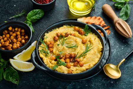 Foto de Hummus vegetariano tradicional con garbanzos en un tazón. Vista superior. Sobre un fondo de piedra negra. - Imagen libre de derechos