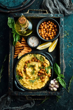 Téléchargez les photos : Hummus végétarien traditionnel avec pois chiches dans un bol. Vue de dessus. Sur un fond de pierre noire. - en image libre de droit
