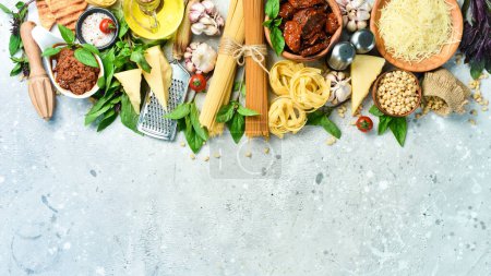 Photo for Food banner. Italian traditional cuisine: pesto sauce, pasta, basil, parmesan and nuts, olive oil. On a concrete background. Top view. - Royalty Free Image