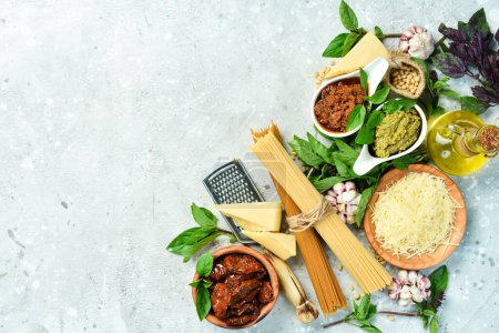 Photo for Preparation of spaghetti: pesto sauce, pasta, basil, parmesan and nuts, olive oil. On a concrete background. Top view. - Royalty Free Image