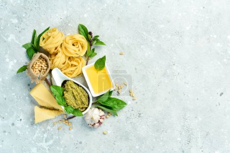 Photo for Cooking background: pesto sauce, pasta, basil, parmesan and nuts, olive oil. On a concrete background. - Royalty Free Image