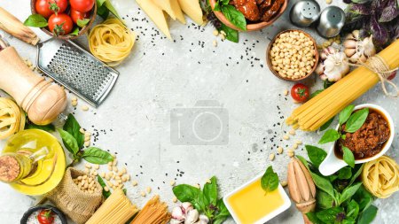 Téléchargez les photos : Fond de cuisson : sauce pesto, pâtes, basilic, parmesan et noix, huile d'olive. Sur un fond concret. - en image libre de droit