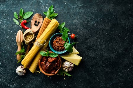 Photo for Cooking spaghetti with pesto sauce and sun-dried tomatoes. Ingredients: Spaghetti, basil, parmesan, pine nuts, tomatoes, spices. Italian traditional cuisine. On a concrete background. - Royalty Free Image