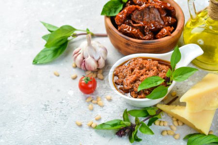 Photo for Preparation of traditional Italian pesto sauce with dried tomatoes. Ingredients: basil, parmesan, pine nuts, tomatoes, spices. On a concrete background. - Royalty Free Image