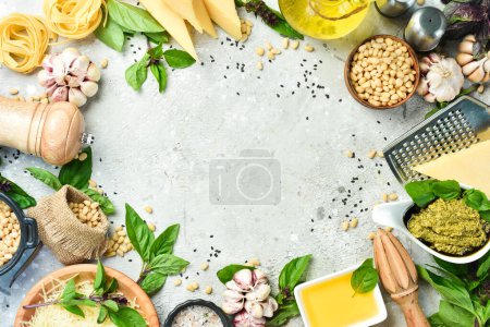 Foto de Preparación de salsa de pesto. Ingredientes: Albahaca, piñones, parmesano y aceite de oliva. Sobre un fondo gris de hormigón. - Imagen libre de derechos