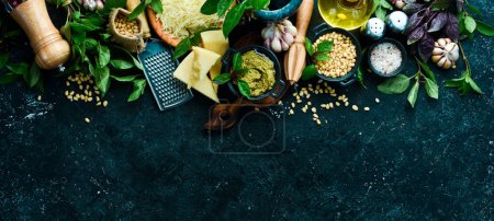 Photo for Traditional pesto sauce. Ingredients: Basil, pine nuts, Parmesan and olive oil. On a black stone background. - Royalty Free Image