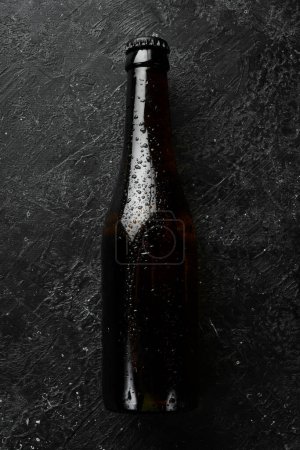 Foto de Lúpulo fresco, vasos y cerveza. Cerveza oscura en botellas de vidrio sobre un fondo de piedra negra. Banner de cerveza. - Imagen libre de derechos