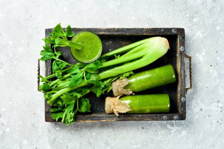 Photo for A bottle of celery juice in a box on a stone background. Vegetarian drink. A stalk of fresh celery. Free space for text. - Royalty Free Image