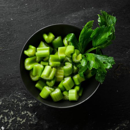 Photo for A stalk of fresh celery cut into pieces in a bowl. Dietary healthy food. Free space for text. - Royalty Free Image