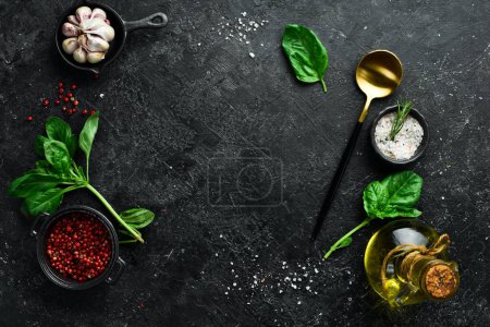 Photo for Cooking background: cutlery, spices and basil. On a black stone background. - Royalty Free Image